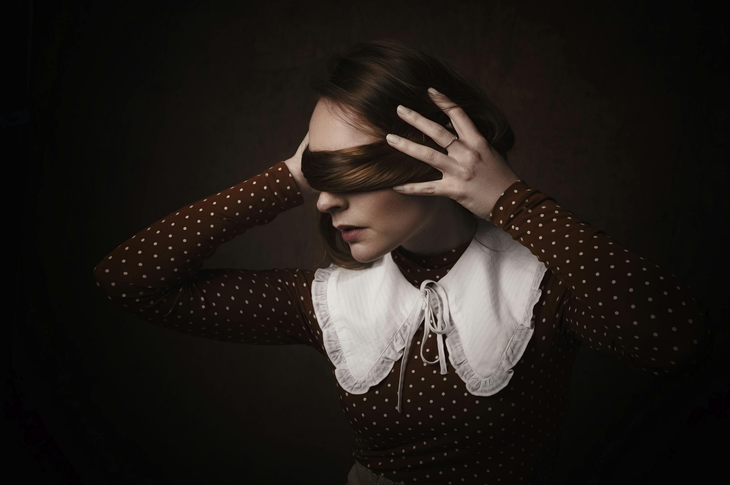 A dramatic and conceptual portrait of a woman blindfolded by her own hair, creating a mysterious atmosphere.