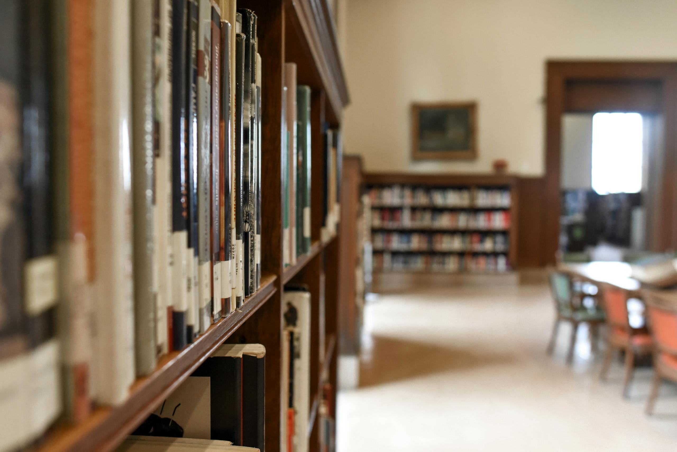 A quiet library interior featuring bookshelves, seating, and a study area for learning and reading.