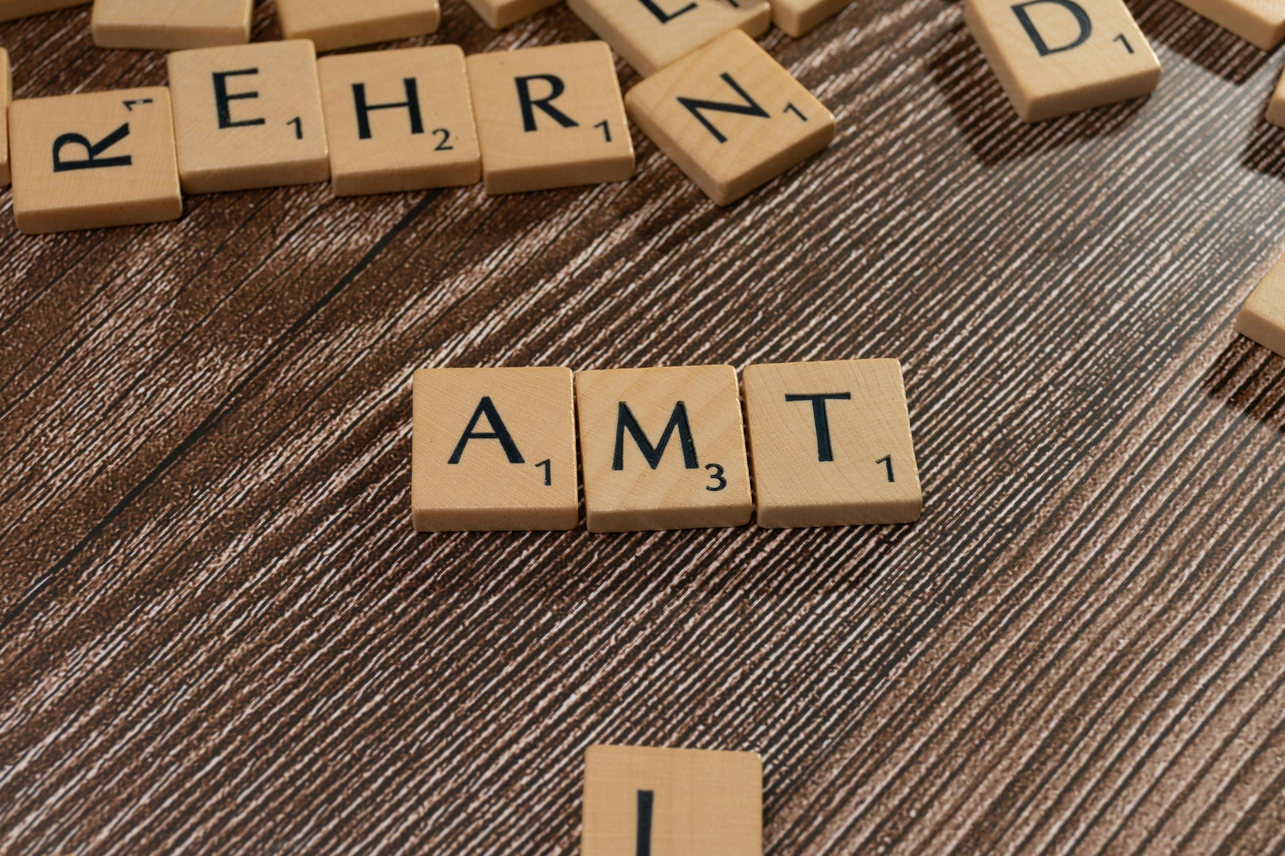 Close-up of Scrabble tiles scattered on a wooden table, forming words.