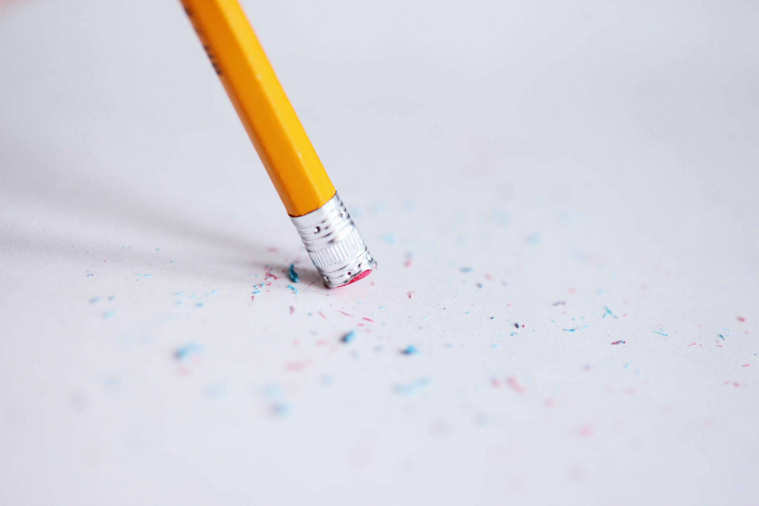 Macro shot of a yellow pencil erasing on paper with eraser shavings.